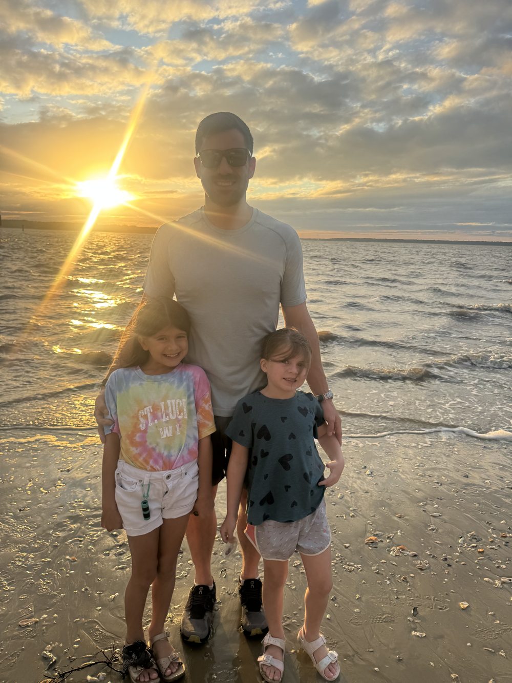 Chris and his daughters at the beach at sunset